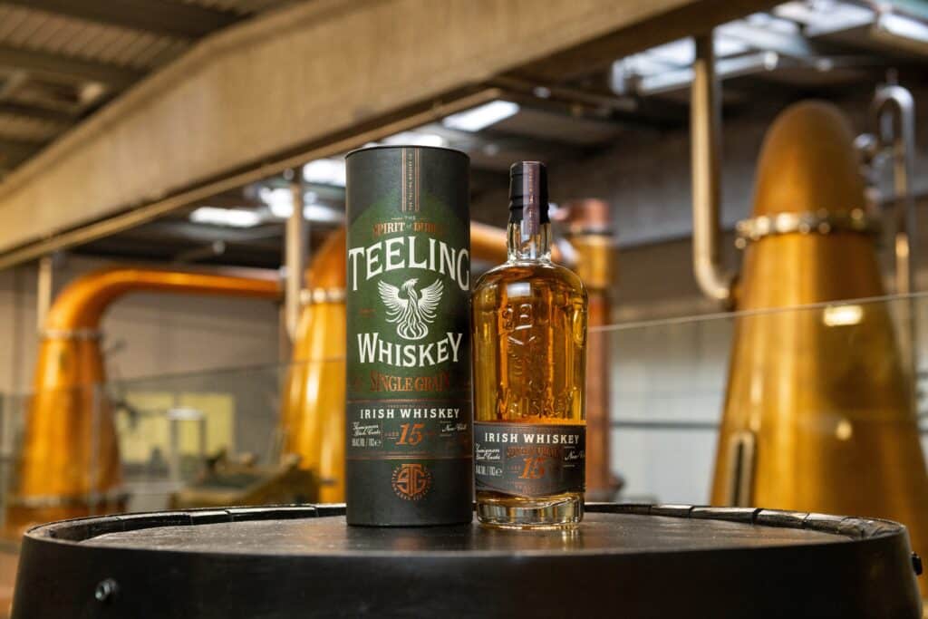 Teeling Single Grain 15 Year Old in front of pot stills in Teeling Whiskey distillery